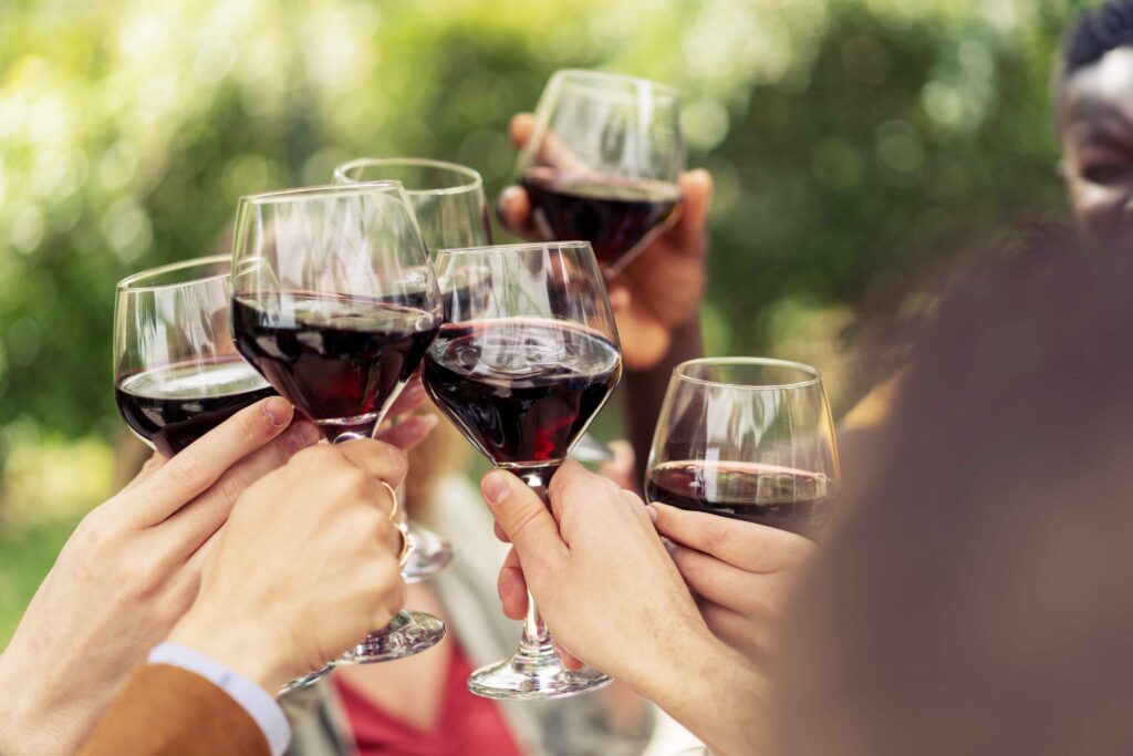Close-up of friends toasting with red wine in an outdoor celebration