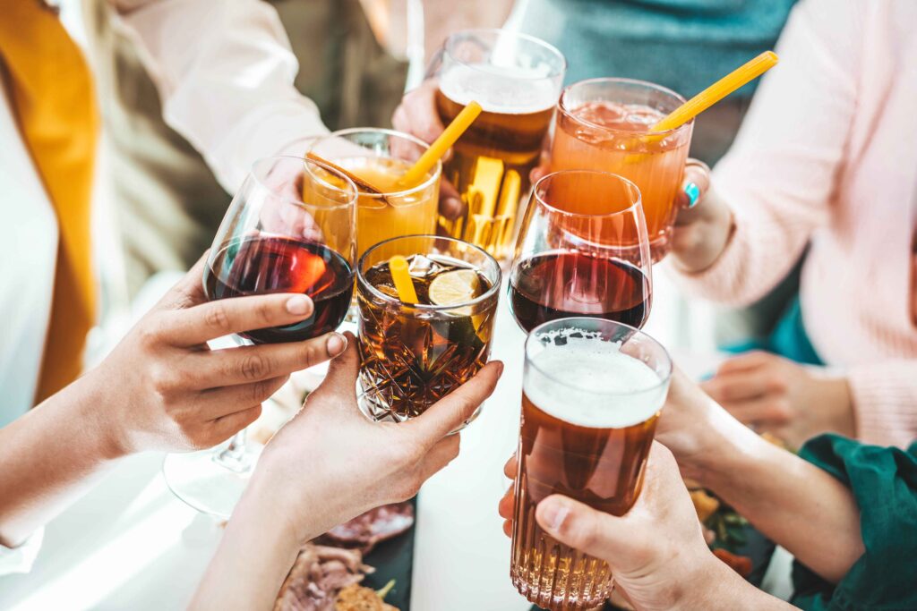 Close up image of hands holding cocktail glasses at bar