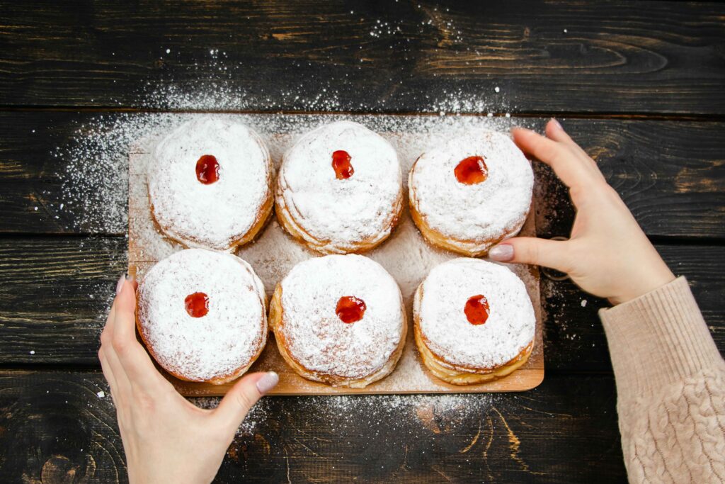 woman sprinkling powdered sugar on sufganiyot