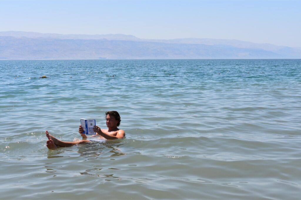 man floating in the dead sea while reading a book